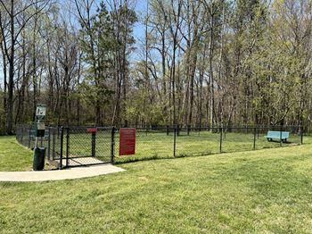 A park with a fence, a bench, and a sign.